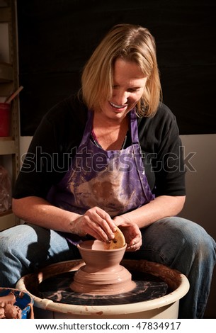 Female potter working with clay on wheel in studio