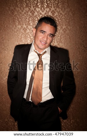 Handsome Hispanic man in suit against gold wallpaper background