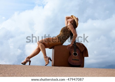 Pretty brunette woman with suitcase and guitar