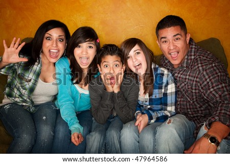stock photo Hispanic Family with Big facial Reactions Sitting on Couch