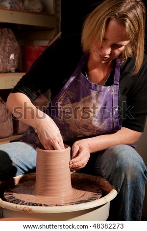 Female potter at wheel in studio shaping clay
