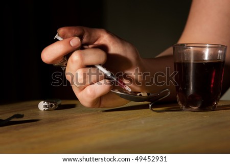 Closeup of woman\'s hand drawing black tar heroin into a needle