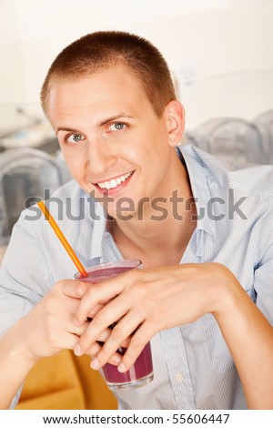 A young man holding a frozen beverage. Vertical shot.