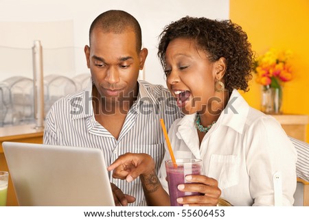 Two people at a cafe drinking frozen beverages and using a laptop. Horizontal shot.