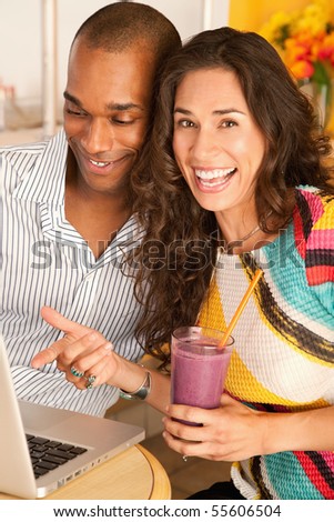 Two people at a cafe drinking frozen beverages and using a laptop. Vertical shot.