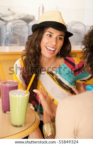 Two young women at a cafe drinking frozen beverages. Vertical shot.