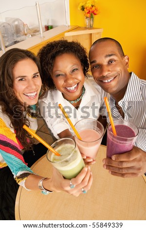 High angle view of three people at a cafe drinking frozen beverages. Vertical shot.