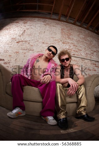 Two cool party goers sitting on a sofa