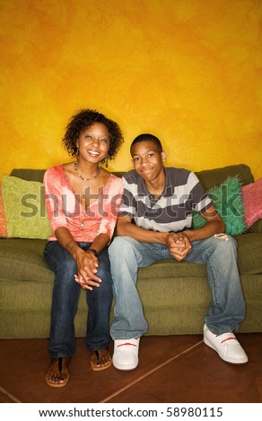 Good-looking single-parent mom and son sitting on sofa