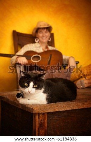 Pretty western woman in antique rocking chair with guitar and cat