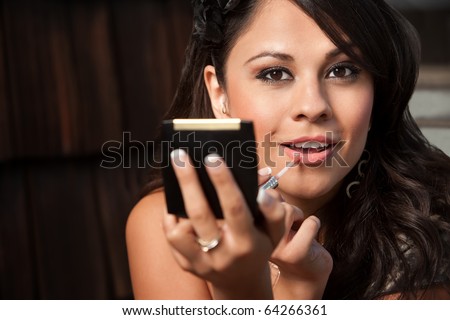 Beautiful Latina Woman Looking into Compact Mirror and Applying Lip Gloss