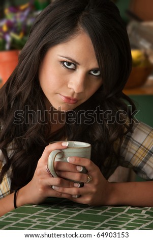 Beautiful Sad or Serious Latina Woman at Table in Kitchen with Coffee or Tea