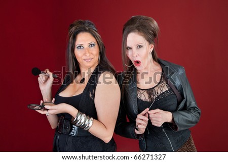 Two middle-aged ladies dressed in black prepare their makeup