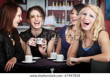 Pretty young blonde laughing with three friends in a cafe