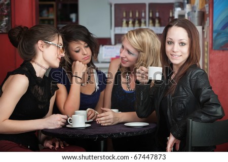 A confident young woman drinks coffee with friends in a cafe