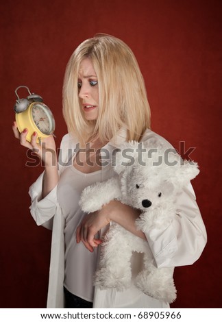 Pretty blond woman with bear and clock wakes up late