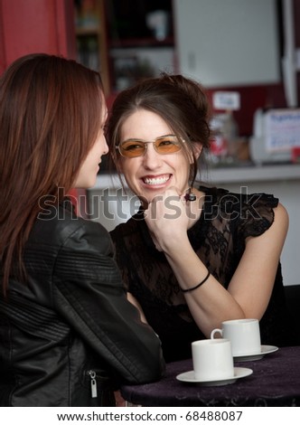 A cute young lady laughing with her friend at a coffee bar