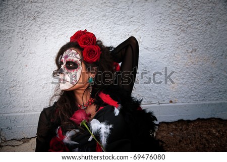 Pretty Middle Aged Lady With Roses and Wearing Makeup for All Souls Day alongside a wall