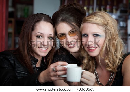 Three cute teenaged friends smiling and saying cheers over coffee