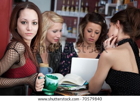 Cute looking young girl with her friends in a cafe discussing a project