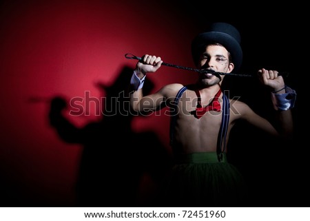 Performer in top hat biting leather whip
