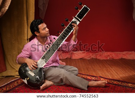 Handsome young Indian man plays a Sitar