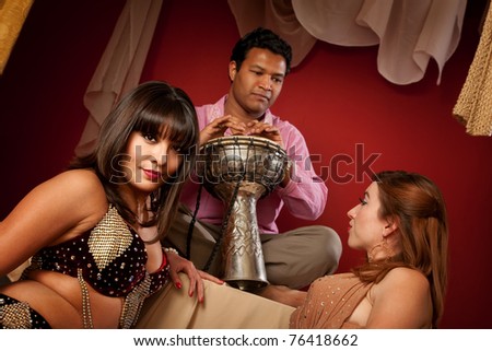 Two beautiful belly dancers with handsome Indian tabla player