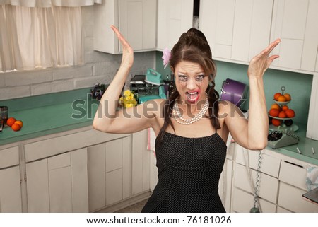 Messy housewife in kitchen yells with her hands raised