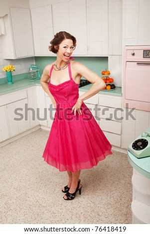 Happy middle-aged woman with hands on hips in retro-styled kitchen scene