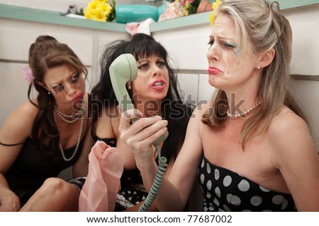 Pouting woman on phone with friends in kitchen
