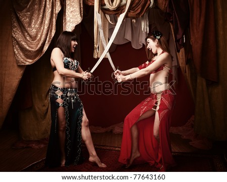 Two beautiful Arab belly dancers sword fighting