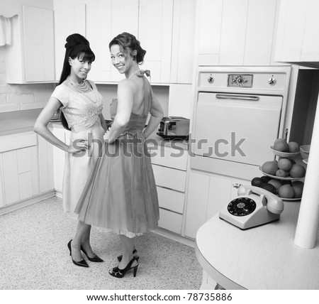 Happy Caucasian housewives in a retro kitchen with hand on hips