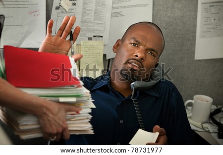 Black office worker with heavy workload on a phone call