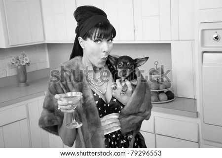 Middle-aged woman in fur coat with martini kisses a Chihuahua dog