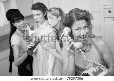Excited woman on phone while friends drink and smoke in the kitchen