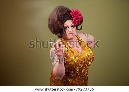 Serious drag queen smoking cigarette on green background