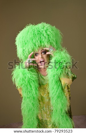Emotional drag queen in boa and wig on green background