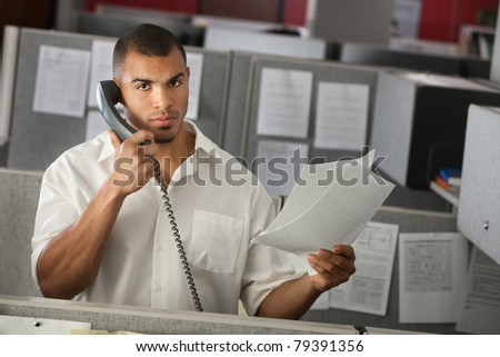 Serious office worker on a phone call with documents in his hand