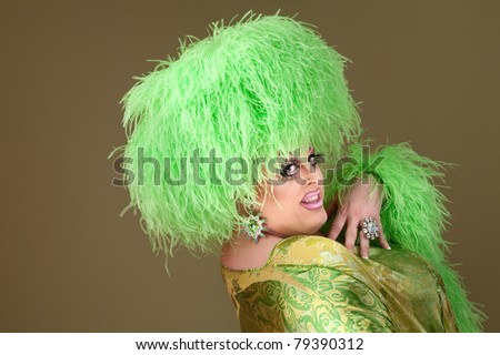 Drag queen with makeup and green fluffy wig smiles