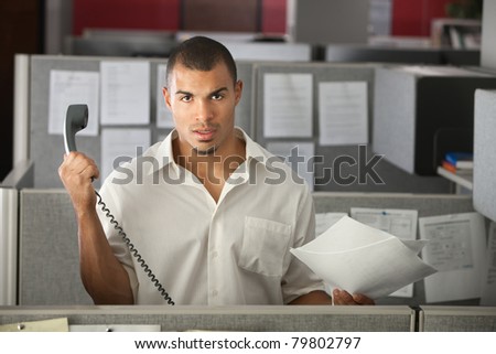 Frustrated office worker with papers holds a phone away from his ear