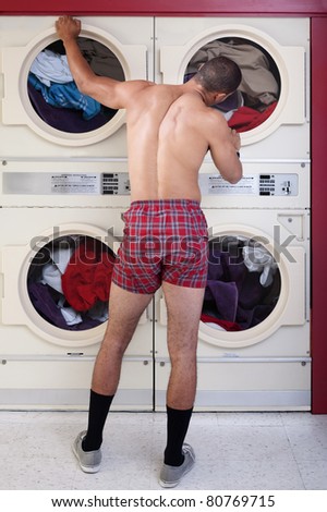 Muscular man in boxer shorts stands waits by a clothes dryer