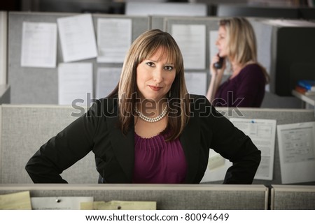 Confident woman office worker stands in her cubicle