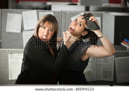 Two female office workers fight in a cubicle