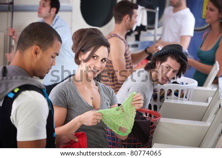Beautiful Caucasian stares at handsome Black man with panties in her hands at the Laundromat