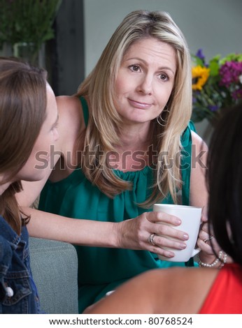 Middle-aged woman smirks while talking with friends