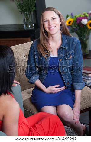 Beautiful pregnant woman with friend relaxes on a chair