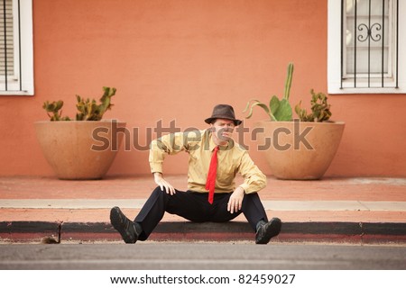 Caucasian businessman with raised eyebrow sits on the street