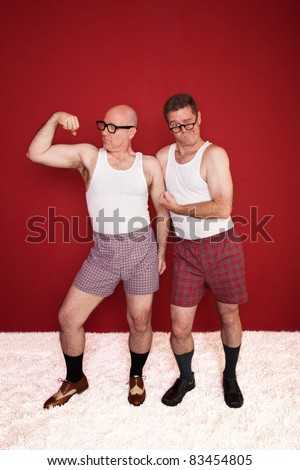 Two middle-aged men in boxers flex their muscles