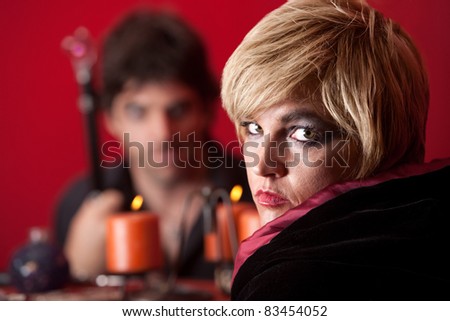 Serious Caucasian woman fortuneteller stares over maroon background