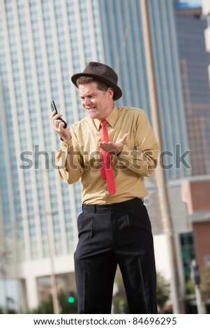 Upset Caucasian businessman with mobile phone on street